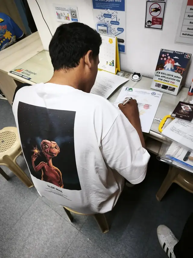 Applicant filling out a form at a visa application counter
