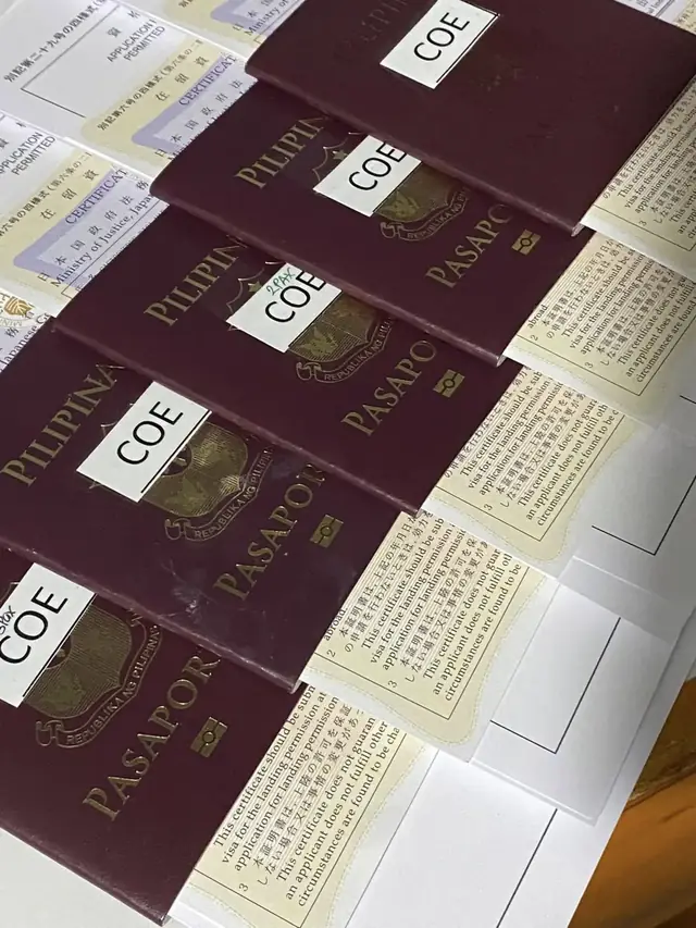 Close-up of passports labelled COE stacked on paperwork