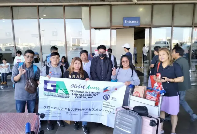 GLOBAL ACCESS participants and staff with the GLOBAL ACCESS banner at an airport entrance
