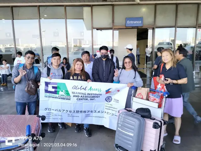 Group with luggage trolleys and the GLOBAL ACCESS banner at the airport entrance