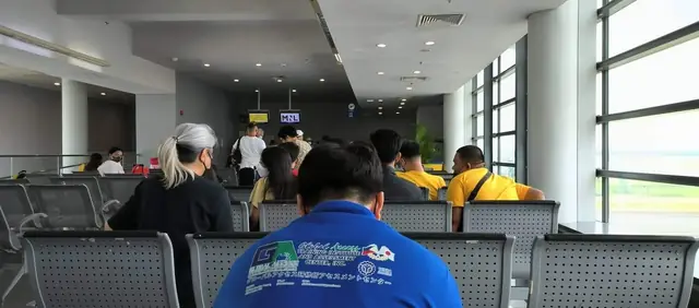 Participant in a blue GLOBAL ACCESS shirt waiting in the departure lounge