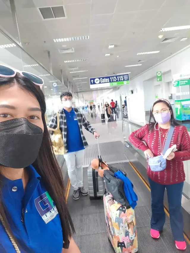 Participants with luggage walking toward the boarding gates