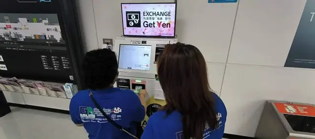 Participants using a currency exchange machine marked Get Yen