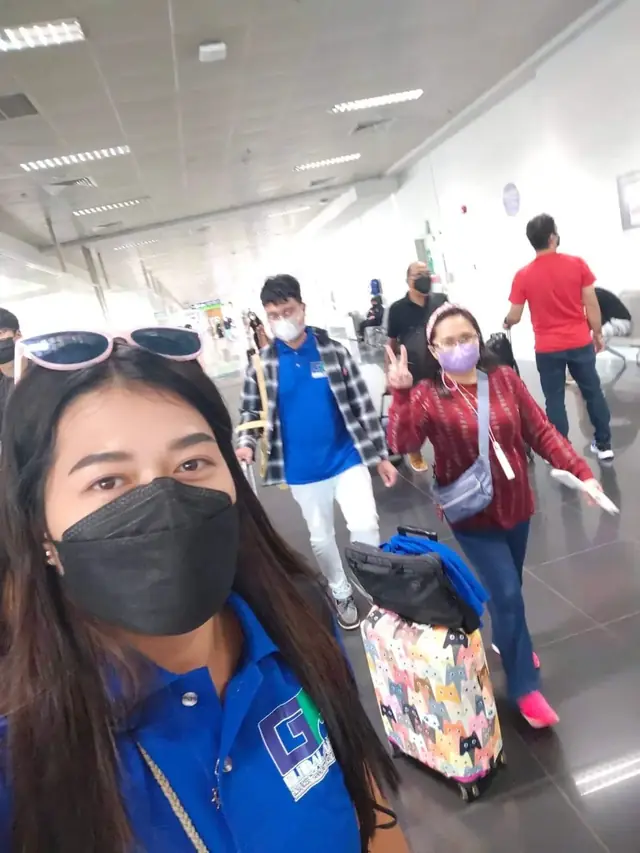 Selfie with a participant pulling a colorful suitcase through the terminal