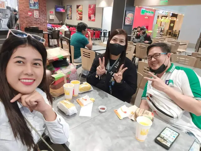 Staff and participants smiling over a meal at an airport food court
