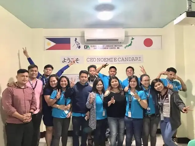 Staff and trainees posing together under a Philippines–Japan welcome sign at the training center