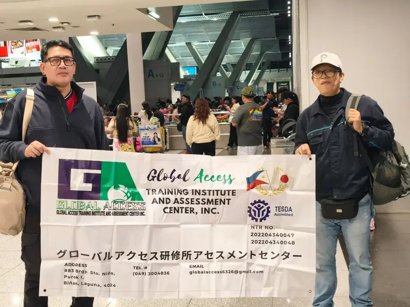 Two men holding the GLOBAL ACCESS banner in the airport terminal
