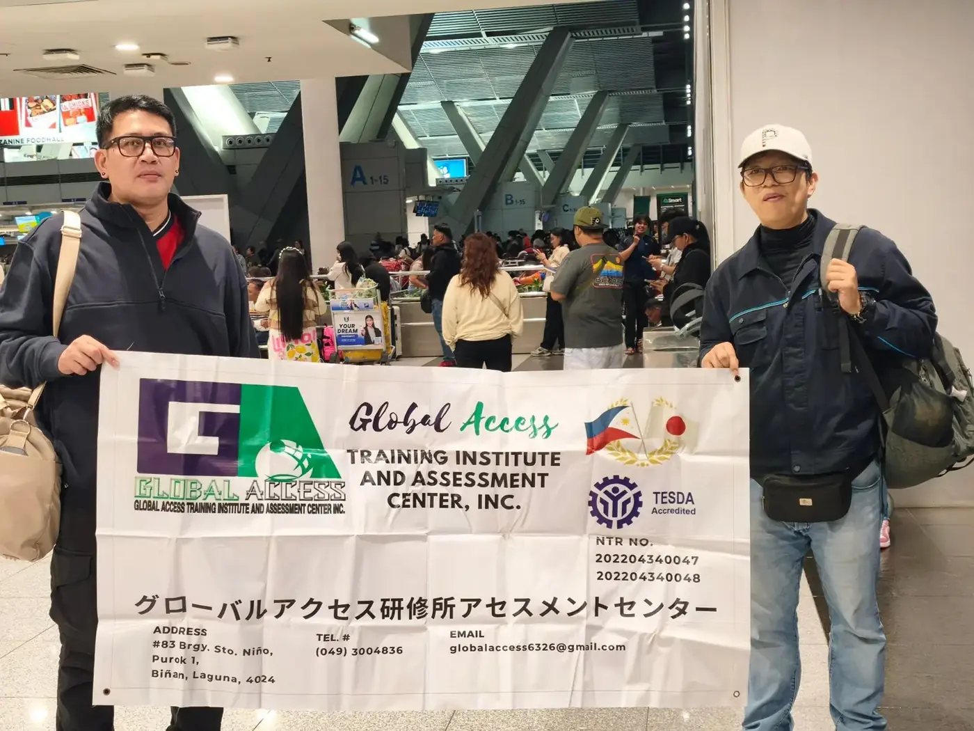 Two GLOBAL ACCESS representatives holding the GLOBAL ACCESS banner inside an airport terminal