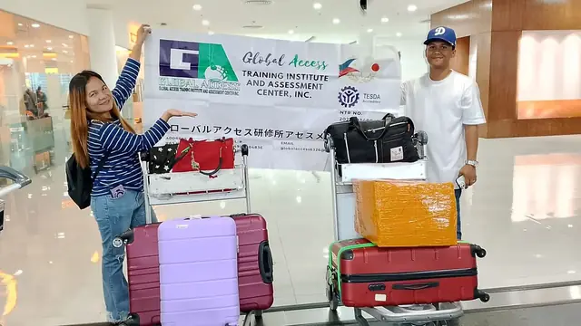 Two participants with colorful luggage and the GLOBAL ACCESS banner