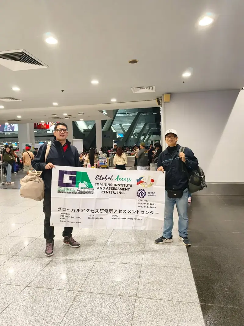 Two travelers standing behind the GLOBAL ACCESS banner in the airport hall